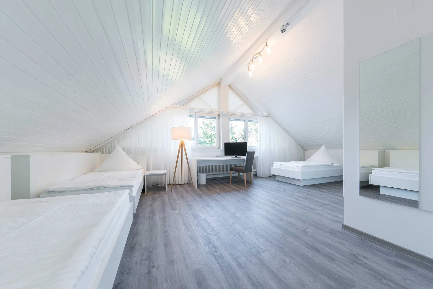 Helles Dachgeschosszimmer mit Dachschräge, Betten und Schreibtisch