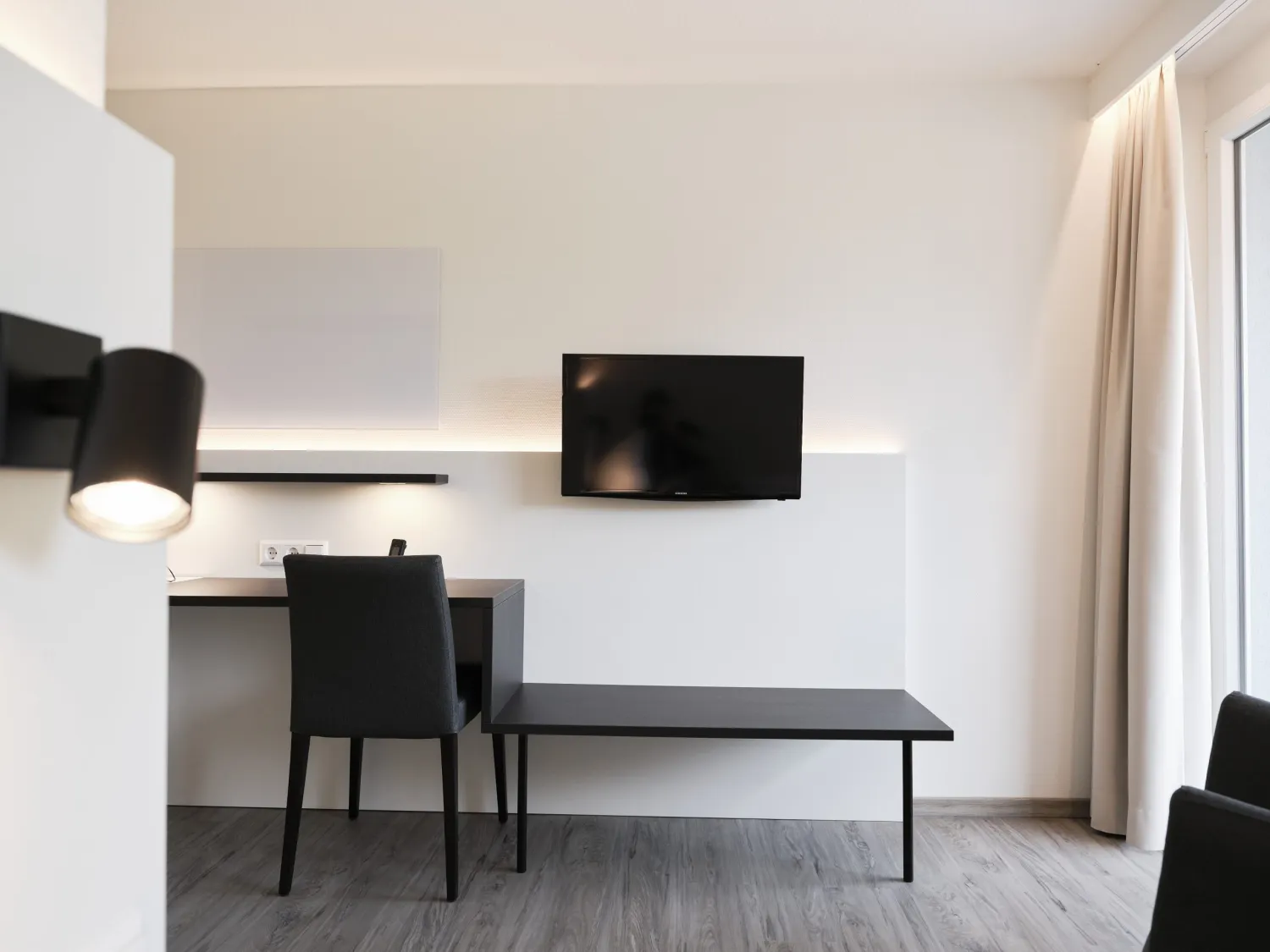 Arbeitsplatz mit Schreibtisch und Wand-TV im Patientenzimmer